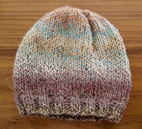 A plain knit hat, small, with softly stripy pary in various pastels in earthy tones.