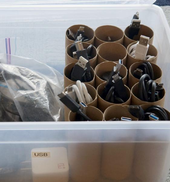 a plastic bin, half full of toilet paper rolls glued together, with a cable in each roll